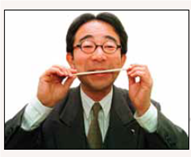Why Do They Have to Learn to Smile? In the United States it's very common to see people smiling in public because it's a friendly way to interact socially. In fact, many businesses insist that their salespeople smile at customers because smiling makes the customers feel more comfortable and more likely to buy something. But in Japan, people are very reluctant to show emotions in public and that's become a problem. Japan is currently going through a recession or downturn in business, so there is increased competition to get new customers and keep current customers happy. Said one gas station attendant who is trying to learn to smile more, In this recession, customers are getting choosy about their gas stations, so you have to think positively. Laughter and a smile are representative of this positive thinking (Reitman, 1999, p. A1). But getting salespeople to smile is a radical change in Japan, whose cultural tradition has long emphasized suppressing any public display of emotions, be it happy, sad, or angry. For example, women never smile at their husbands and members of families rarely touch in public and never hug, even when greeting after a long separation. It's still common for women to place a hand over their mouths when they laugh, and men believe that the correct and proper behavior is to show no emotions in public. Unlike American salespeople who often smile and make eye contact with their customers, Japanese salespeople are reserved and greet customers with a simple welcome; smiling, up until now, was totally frowned upon. Because getting salespeople to smile is going against a strong tradition, learning how to smile has grown into a big business in Japan. Employees are now being sent to smile school, which uses various techniques to teach reluctant and bashful students to smile. For example, one technique in learning how to smile is biting on a chopstick (photo above) and then lifting the edges of the mouth higher than the chopstick. Another technique is to follow smile instructions: Relax the muscle under your nose, loosen up your tongue. Put your hands on your stomach and laugh out loud, feeling the 'poisons' escape (Reitman, 1999, p. A1). What is driving all this smiling in Japan is sales and morale. As is well known by American businesses, happy, friendly salespeople are usually the most successful and are great at building company morale. The same is holding true in Japan, where smiley clerks are racking up the most sales and creating a friendly morale. People in other parts of Asia, such as China, also are not accustomed to smiling in social situations. In fact, volunteers for the 2008 Olympics in Beijing were required to take classes on how to smile to ensure that they portray China as hospitable. Question Why is it so difficult for many highly motivated Japanese to learn to smile?