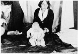 <strong>What is going on in this famous photo? </strong> A)Edward Thorndike's research assistant is investigating the law of effect and trial and error learning in a young child. B)Albert Bandura's research assistant is demonstrating observational learning by showing how this infant lost his fear of a tame lab rat after watching other infants play with the animal. C)Ivan Pavlov and his daughter V.I.Pavlova Pavlov are conducting basic research on classically conditioned responses in an infant. D)John Watson and his graduate student Rosalie Rayner are conducting research on the classically conditioned fear response in their subject, Little Albert.