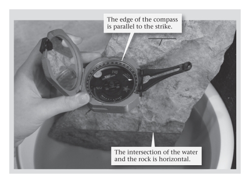 <strong>A geologist's compass differs from the more widely known orienteering compass in that the geologist's compass ____________. </strong> A)possesses an inclinometer,allowing the user to measure dip and plunge angles B)contains a barometer that warns the geologist of approaching storms C)can chemically analyze rock samples in the field D)needle points directly toward geographic north rather than geomagnetic north