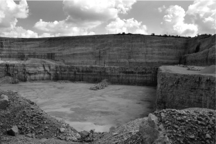 The image below is of a limestone quarry in Illinois.On the wall at the very back of the quarry you can see layers that appear to curve upward.What do these layers represent?  