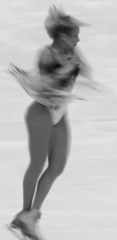 Explain why an ice-skater spins faster when she pulls her arms in compared to when her arms are stretched straight out.