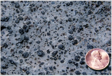 <strong>What does this texture indicate about the formation of this rock?  </strong> A)It formed from an explosive pyroclastic eruption. B)The rock solidified at great depth. C)The magma formed some crystals before rising closer to the surface and solidifying. D)The magma had abundant dissolved gas. <div style=padding-top: 35px> 