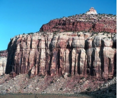 <strong>What are some components of the landscape shown in this photograph? </strong> A) a natural stain on the outside of the rocks B) fractures and layers C) loose rocks covering a slope-forming unit D) rounding of the upper parts of the cliff E) all of these
