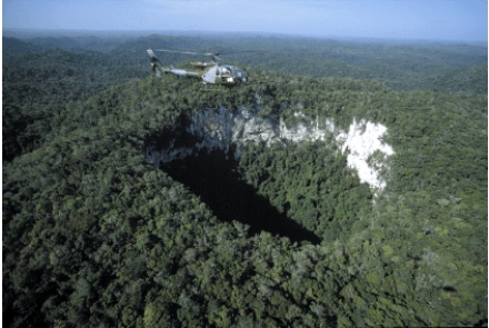 <strong>The feature pictured below is formed as a result of subsurface dissolution of limestone rock which can weaken the overlying material and cause it to collapse. These resulting features are called: </strong> A)caves B)sinkholes C)aquifers D)geysers E)artesian wells