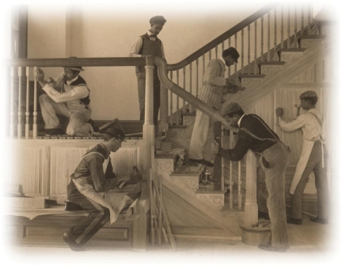 <strong> How does this photograph of a carpentering class at the Hampton Institute reflect Booker T. Washington's ideas of how African Americans should achieve success?</strong> A) It fosters an image of African Americans as superior craftsmen. B) It calms the fears of white supremacists by showing blacks working menial jobs. C) It shows young men working at a trade school to gain skills necessary for advancement. D) It shows young men silently demonstrating their fitness to attend a desegregated school.