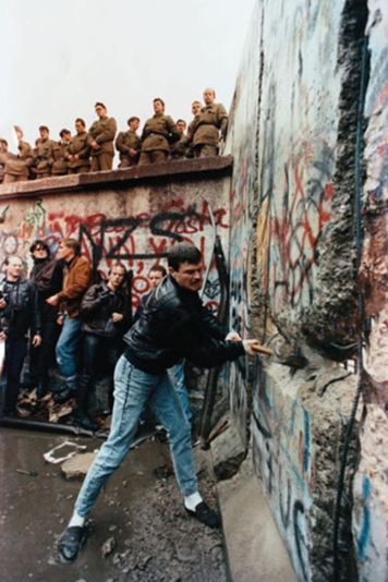 <strong> What does this photograph of one man using a hammer to destroy parts of the Berlin Wall in 1989 symbolize?</strong> A) the frustration shown toward Soviet Premier Mikhail Gorbachev B) the reaction toward the possible retaliation by East German soldiers standing on the wall C) the ability of common people to make history and overcome tyranny D) the anger and resentment that West Germans had toward their countrymen in East Germany