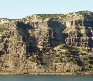 <strong>118)What type of rock likely composes the landscape shown in this photograph from the Investigation? </strong> A)metamorphic rocks B)sedimentary rocks C)granite D)volcanic rocks, probably basalt