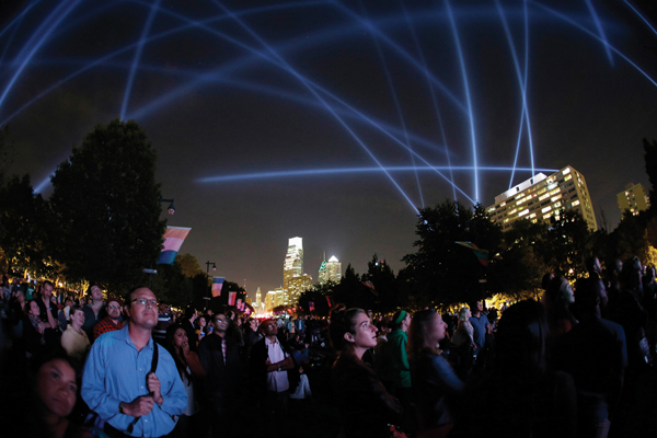 <strong> Why is Lozano-Hemmer's Open Air considered an interactive public artwork?</strong> A)The artwork changed through voice messages that the public sent on their cell phones. B)The public could see their distorted reflection in the artwork. C)The artwork changed as participants wrote their names on a large mural. D)The public could participate in a dance performance choreographed by the artist.