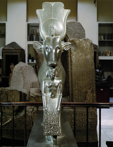 <strong>​   Which element can be seen in the statue The Goddess Hathor and the Overseer of Sealers, Psmatik ?</strong> A)The inspiration from early reed architecture in its decorative patterns B)Lotus bud capitals C)Successively darker, smaller spaces D)The Egyptian use of animal forms to depict deities <div style=padding-top: 35px> 