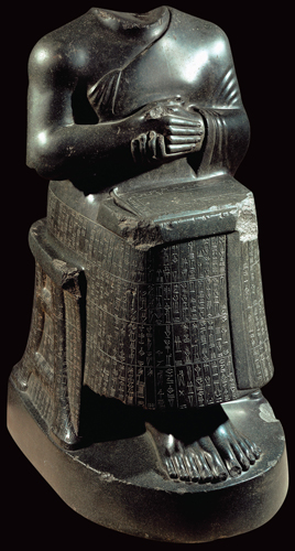 <strong> What appears on the lap of the figure in this statue?</strong> A) The gardens of Babylon B) The colonnade at Persepolis C) The name of the sculptor D) A temple plan